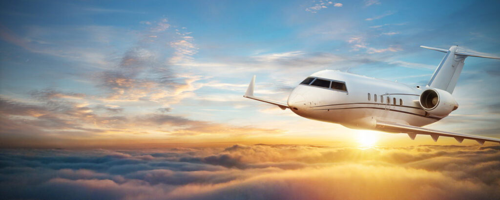 Private jet flying above the clouds during sunset, representing private jet ownership and luxury air travel.
