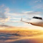 Private jet flying above the clouds during sunset, representing private jet ownership and luxury air travel.